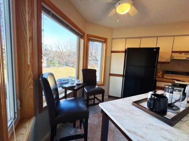 kitchen with ceiling fan, black fridge, and exhaust hood