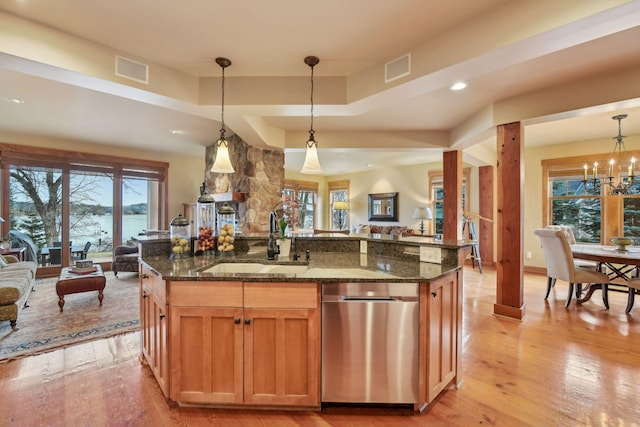 kitchen featuring sink, pendant lighting, dark stone counters, and an island with sink