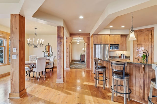 kitchen with decorative light fixtures, decorative columns, dark stone countertops, and appliances with stainless steel finishes