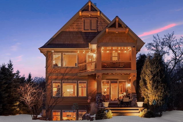 back house at dusk featuring a balcony