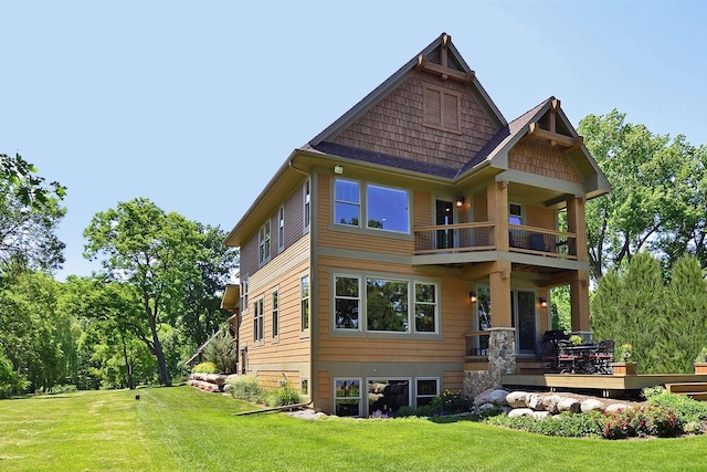 rear view of house with a balcony and a lawn