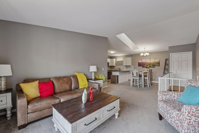 living room with a chandelier, light carpet, a skylight, and sink