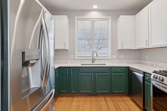 kitchen with green cabinets, white cabinetry, appliances with stainless steel finishes, and a sink