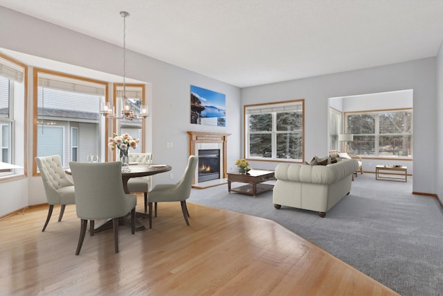 dining space featuring a notable chandelier, wood finished floors, baseboards, and a glass covered fireplace