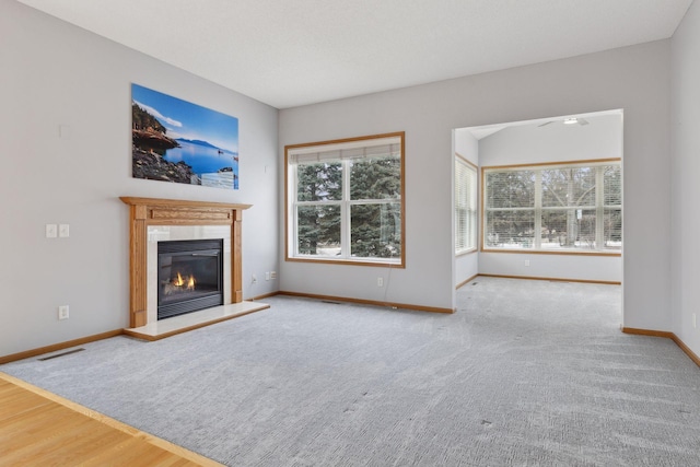 unfurnished living room with a glass covered fireplace, baseboards, visible vents, and wood finished floors