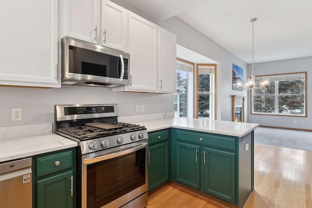 kitchen featuring a chandelier, appliances with stainless steel finishes, a peninsula, light wood-style floors, and white cabinets