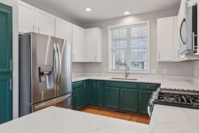 kitchen featuring white cabinets, stainless steel appliances, green cabinets, and a sink