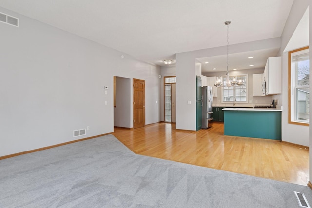 kitchen with visible vents, an inviting chandelier, open floor plan, and stainless steel appliances