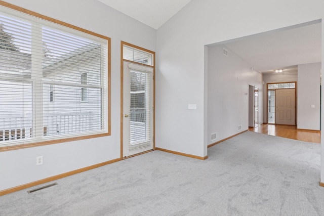 unfurnished room with carpet flooring, visible vents, baseboards, and lofted ceiling