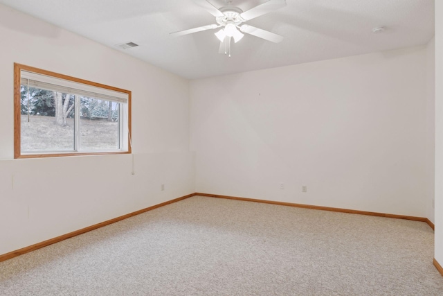 carpeted empty room featuring visible vents, a ceiling fan, and baseboards