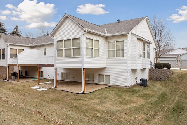 rear view of house featuring a yard, central AC unit, and a shingled roof