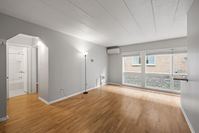 spare room featuring hardwood / wood-style flooring and a wall unit AC