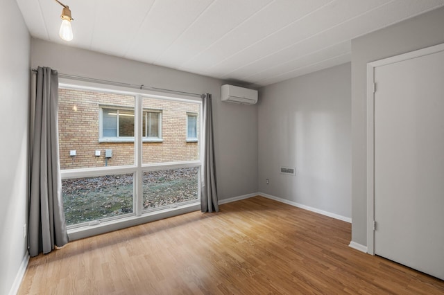 unfurnished room featuring a wall mounted air conditioner and hardwood / wood-style flooring