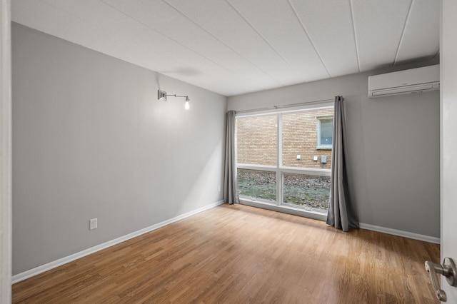 empty room featuring light wood-type flooring and a wall mounted AC