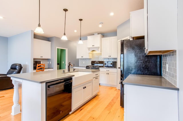 kitchen with pendant lighting, white cabinetry, dishwasher, sink, and a kitchen island with sink