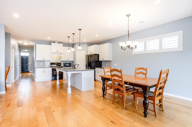 dining room featuring sink, a chandelier, and light hardwood / wood-style flooring