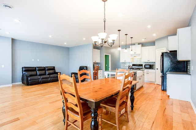 dining area with a chandelier and light hardwood / wood-style flooring