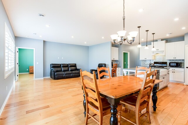 dining room with light hardwood / wood-style floors and a notable chandelier