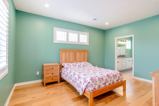 bedroom with sink, ensuite bath, and light hardwood / wood-style flooring