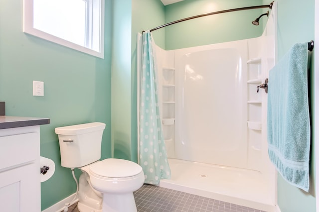 bathroom featuring tile patterned flooring, vanity, toilet, and walk in shower