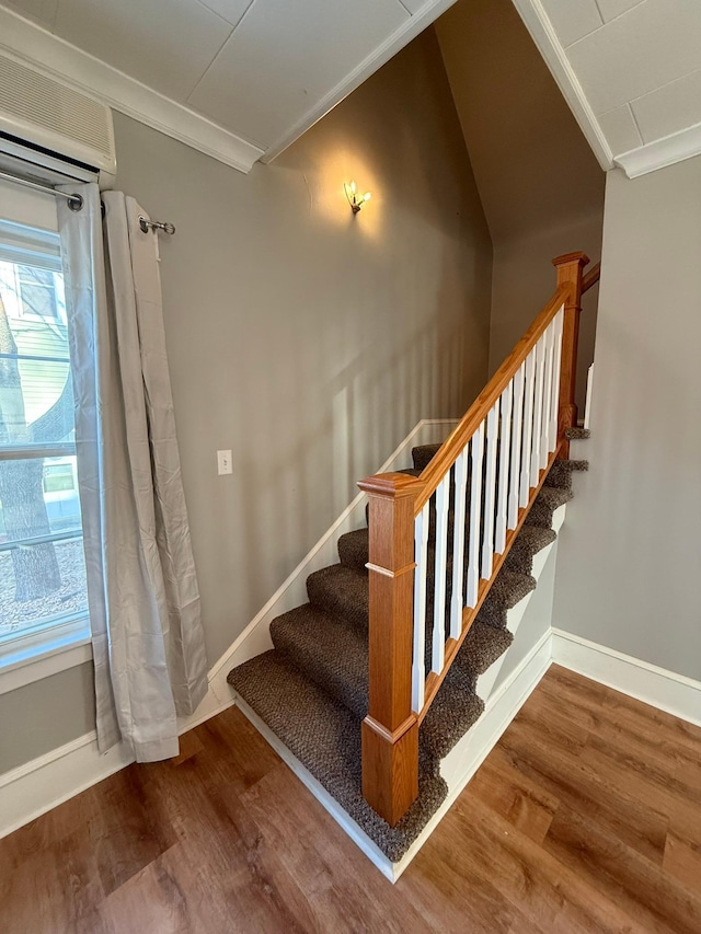 stairway with baseboards, wood finished floors, and crown molding