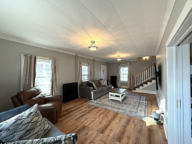 living area with stairs, ornamental molding, radiator heating unit, and wood finished floors