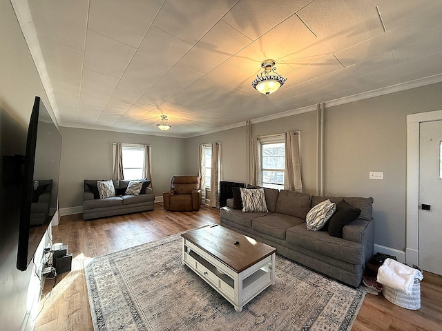 living room with crown molding, plenty of natural light, baseboards, and wood finished floors