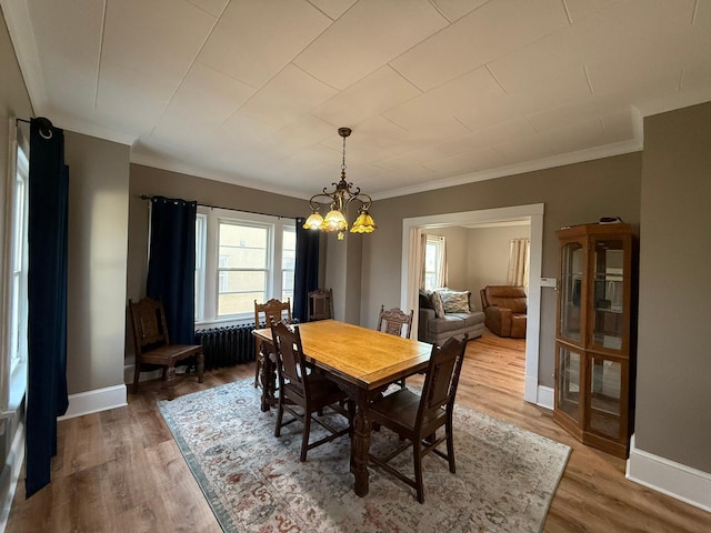 dining area with light wood-style floors, baseboards, and crown molding