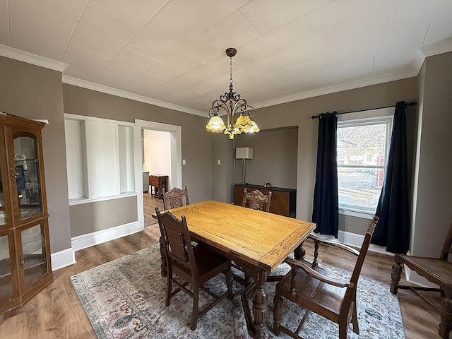 dining area with ornamental molding, wood finished floors, baseboards, and an inviting chandelier