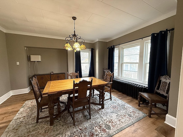 dining area featuring baseboards, radiator heating unit, wood finished floors, crown molding, and a chandelier