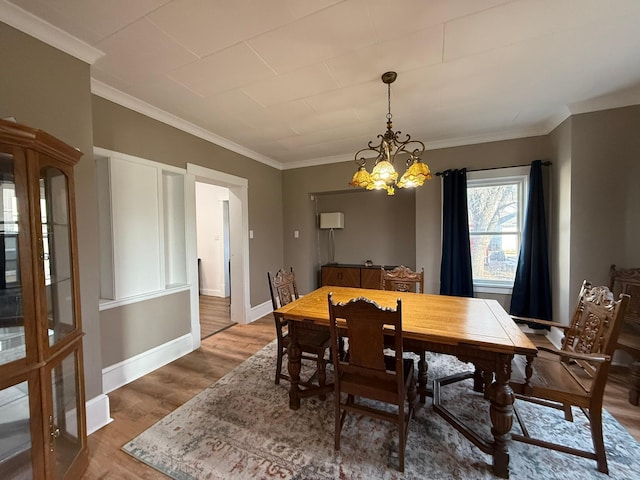 dining room with crown molding, baseboards, a chandelier, and wood finished floors