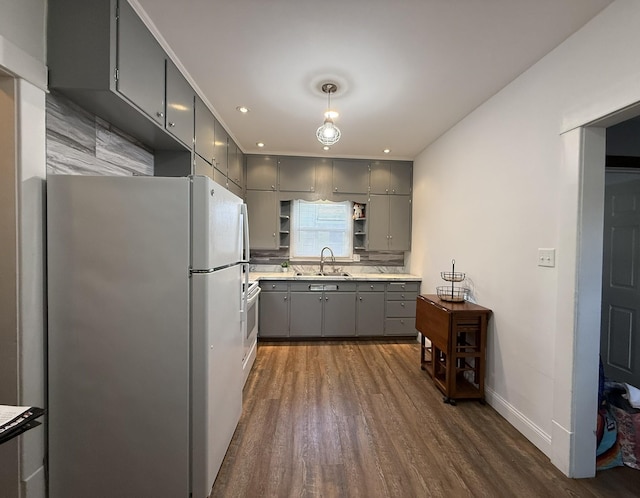 kitchen featuring dark wood finished floors, freestanding refrigerator, gray cabinetry, open shelves, and a sink