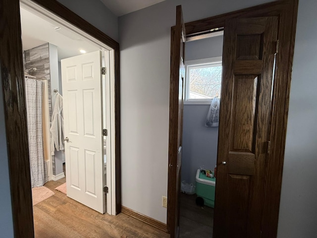 hall featuring light wood-style floors and baseboards