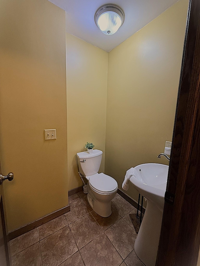 half bathroom featuring toilet, tile patterned flooring, and baseboards