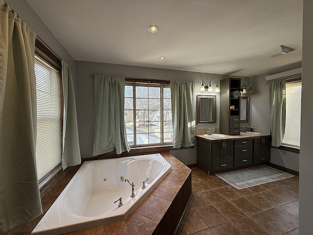 bathroom with double vanity, a jetted tub, a sink, and visible vents