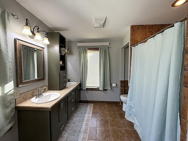 bathroom with baseboards, a sink, toilet, and double vanity