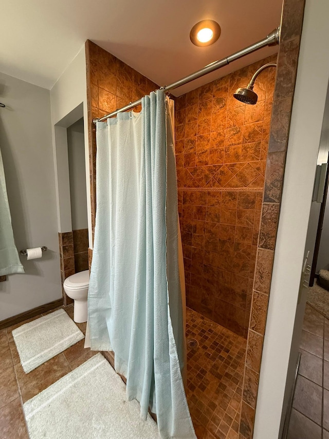 bathroom with tile patterned flooring, a tile shower, and toilet