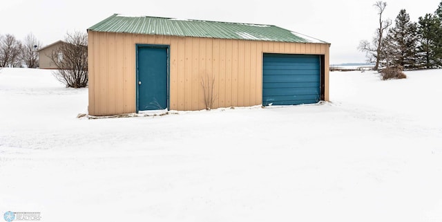 snow covered structure featuring a garage