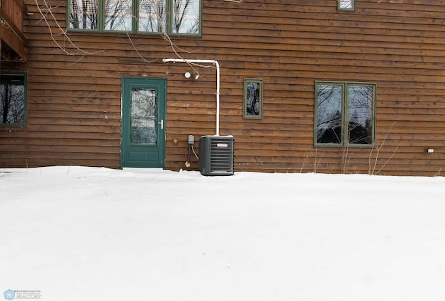 snow covered property entrance featuring central AC