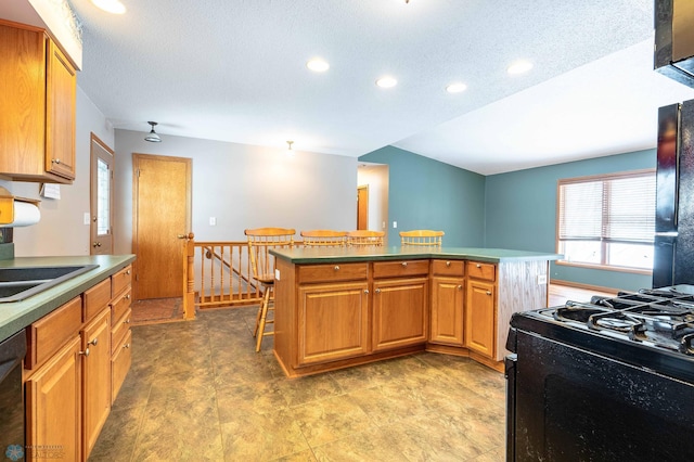 kitchen featuring a kitchen breakfast bar, a kitchen island, black appliances, and a textured ceiling