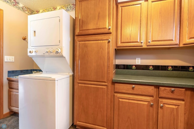 washroom featuring cabinets, stacked washing maching and dryer, and dark wood-type flooring