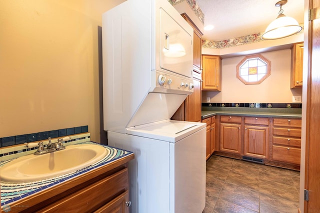 laundry room with a textured ceiling, sink, and stacked washer and clothes dryer