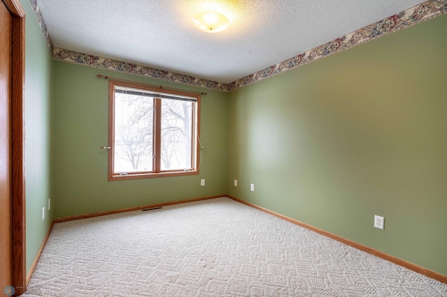 spare room featuring light carpet and a textured ceiling