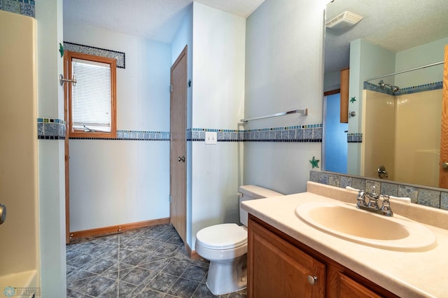 bathroom with vanity, a textured ceiling, toilet, and walk in shower