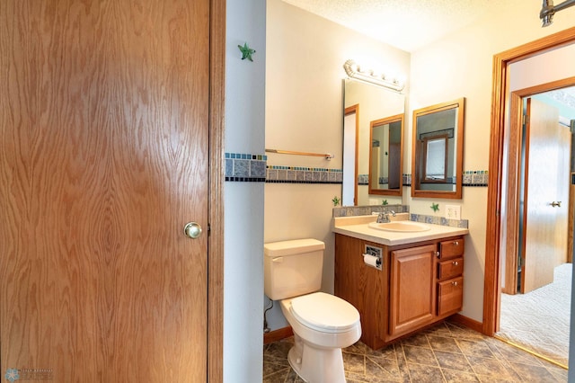 bathroom with vanity, toilet, and a textured ceiling