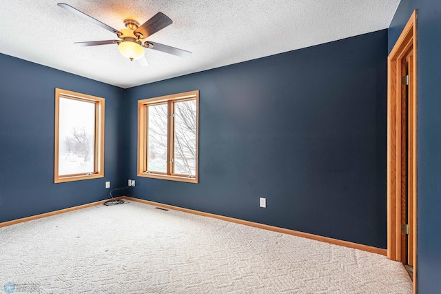 carpeted spare room with a textured ceiling and ceiling fan