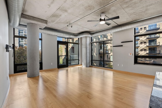 unfurnished living room featuring decorative columns, ceiling fan, and wood-type flooring