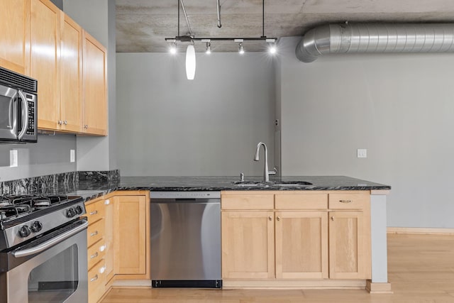 kitchen with light brown cabinetry, sink, dark stone countertops, and stainless steel appliances