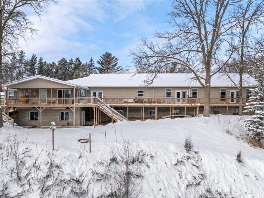 snow covered back of property featuring a deck