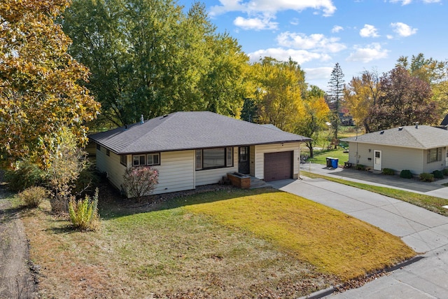 single story home featuring driveway, a front lawn, roof with shingles, and an attached garage